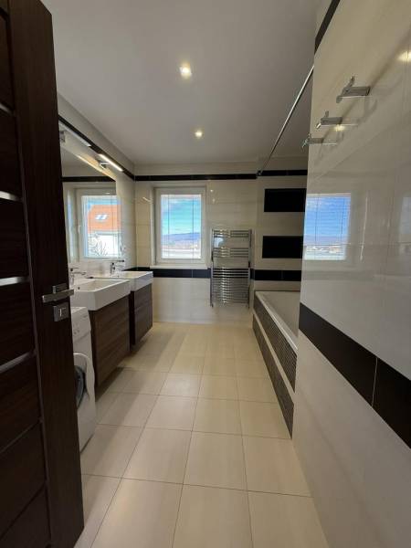 Koupelna ve 4-pokojovém bytě s vanou, umyvadly a pračkou.