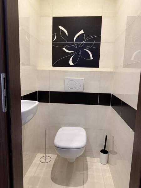 Koupelna se závěsným WC a umyvadlem ve 4pokojovém bytě, zdobená květinovým motivem.