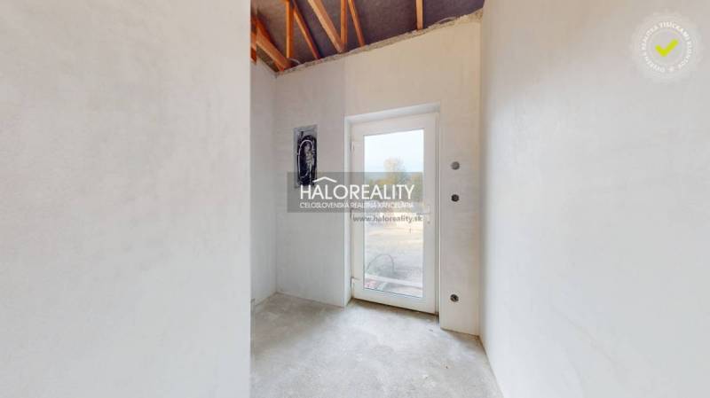 Světlá místnost v rodinném domě s betonovou podlahou a skleněnými dveřmi.