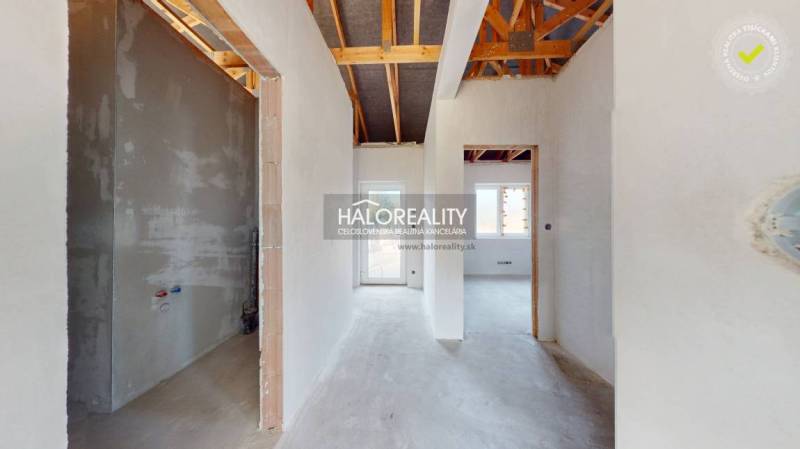 Interiér rodinného domu s pohledem na přechodové chodby a odkrytou střešní konstrukci.