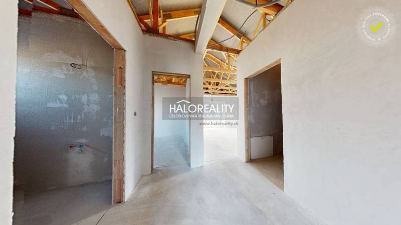 Nedokončený interiér rodinného domu s dřevěnou konstrukcí střechy a otevřenými místnostmi.