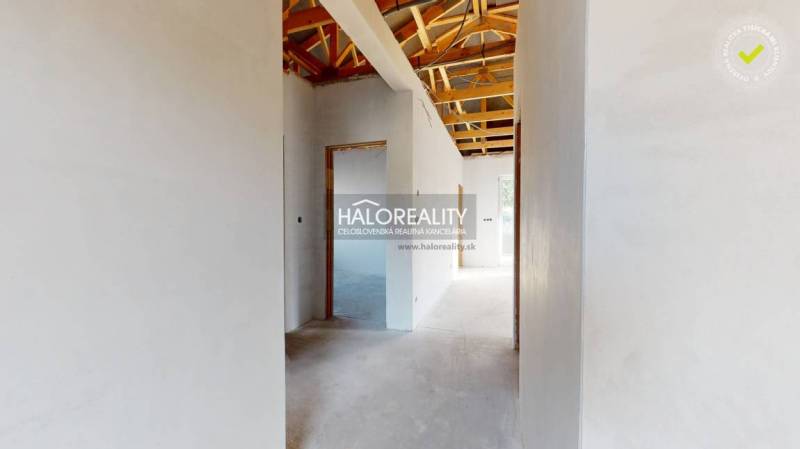 Interiér rodinného domu se střešní konstrukcí a bílými omítnutými stěnami.