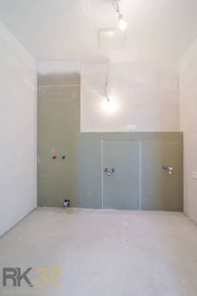 Prázdná místnost v 3-pokojovém bytě ve výstavbě s přípojkami na instalace.