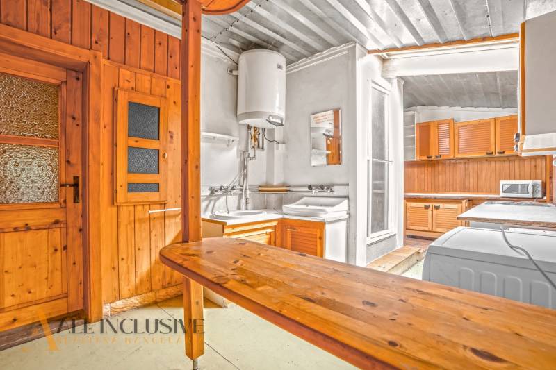 Kuchyně v rodinném domě s dřevěným obkladem a praktickým vybavením.