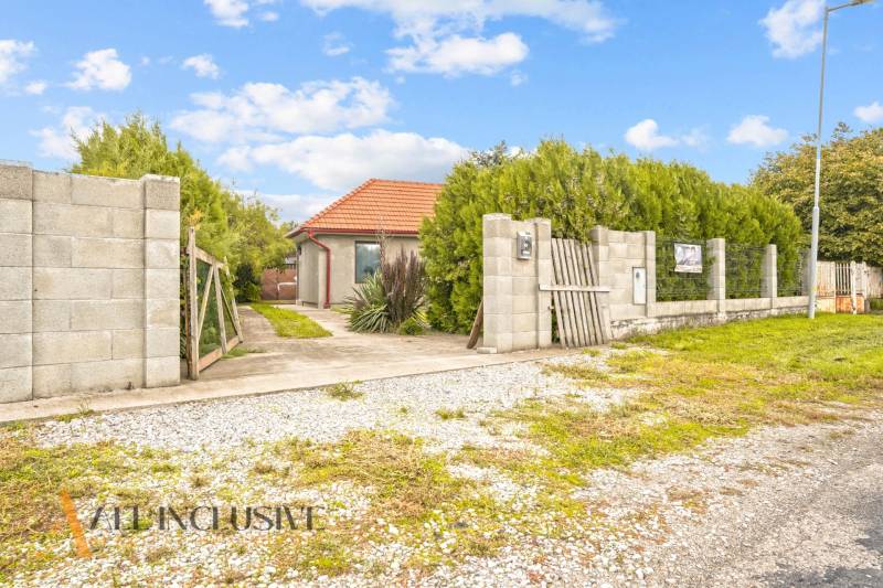 Rodinný dům v Bátorových Kosihách, obklopený zelení, s cestičkou vedoucí k bráně.