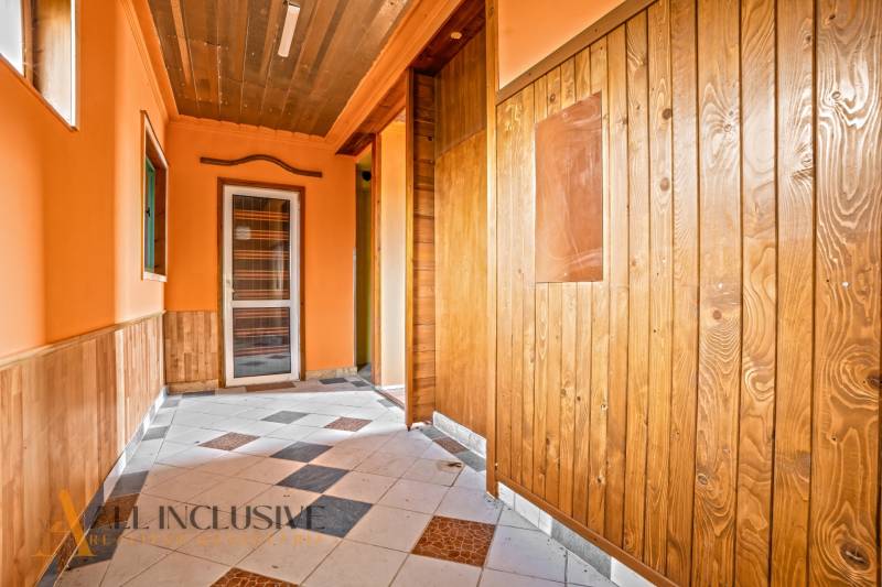 Chodba v rodinném domě s dřevěným obkladem a dlaždicovou podlahou.