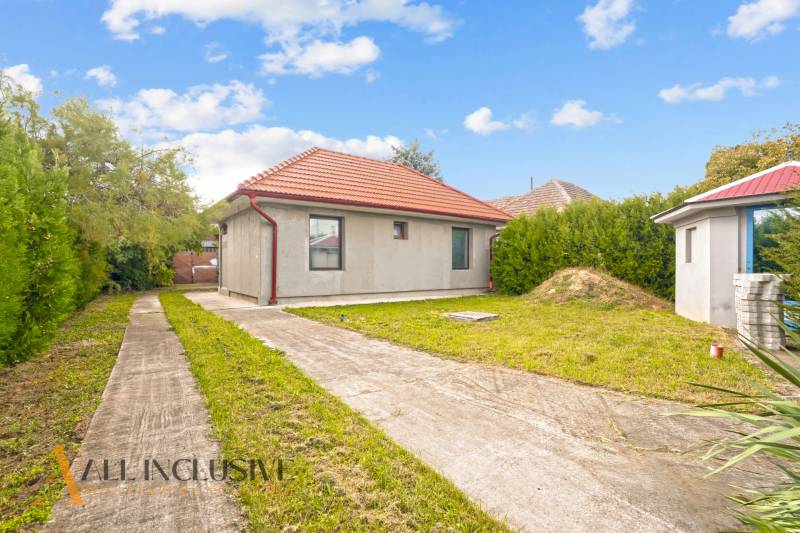 Rodinný dům v Bátorových Kosihách, s trávníkem, betonovým chodníkem a červenou střechou.