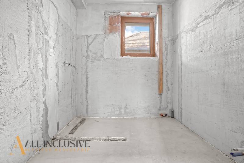 Rekonstrukce koupelny v rodinném domě, stěny z neomítnutého betonu, jediné malé okno.