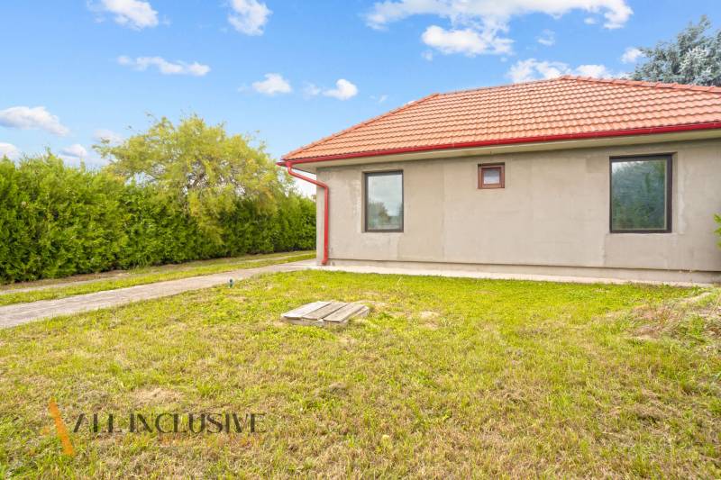 Rodinný dům v Bátorových Kosihách s červenou střechou obklopený zeleným trávníkem a keři.