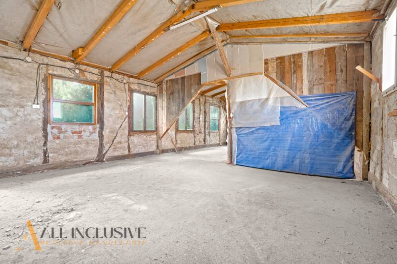 Interiér rodinného domu se surovými stěnami a dřevěnými nosníky.