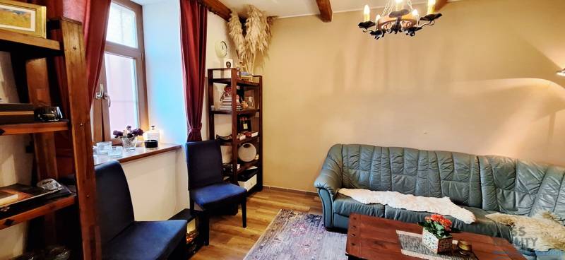 Obchodní prostory se zelenou sedačkou, poličkami a podlahou s dřevěným dekorem.