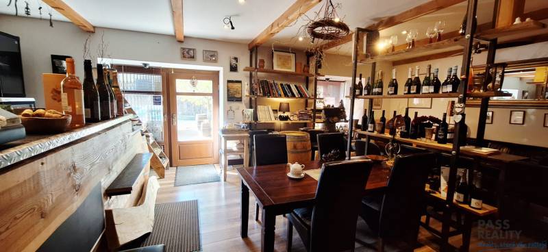 Interiér obchodních prostor s barem, stolem a vinnými policemi, podlaha s dřevěným dekorem.