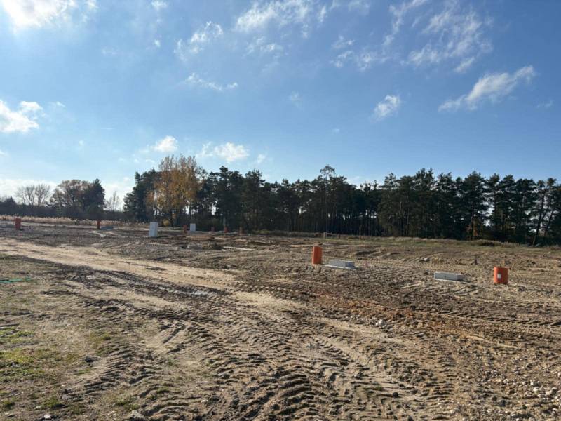 Pozemky na bydlení na ulici Pod Borovicou ve Studienke obklopené stromy a modrou oblohou.