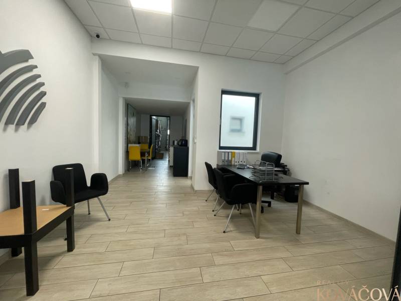 Obchodní prostory s podlahou s dřevěným dekorem, minimalistický nábytek a výrazné židle.