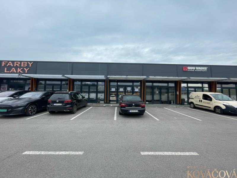 Obchodní prostory na Brněnské ulici v Trenčíně s parkovištěm před prodejnami.