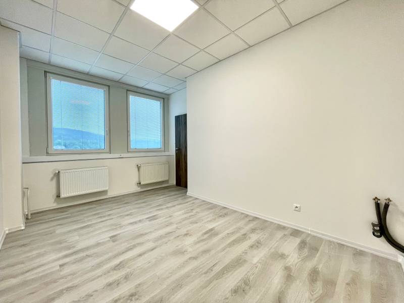 Kanceláře s podlahou s dřevěným dekorem a velkými okny se žaluziemi.