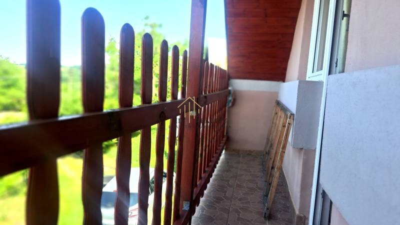 Balkon s výhledem v chatě v Hontianských Trsťanech. Dřevěné zábradlí a dlážděná podlaha.