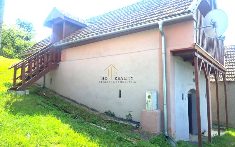 Chata v Hontianských Trsťanech s venkovním schodištěm, trávníkem a satelitní parabolou.