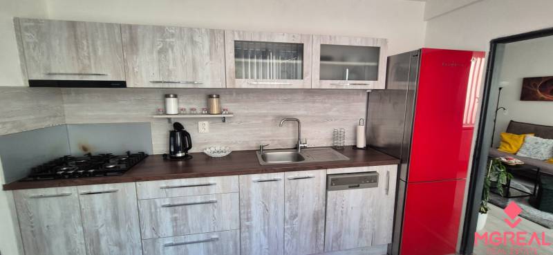 Kuchyně v 2-pokojovém bytě s červenou lednicí a podlahou s dřevěným dekorem.