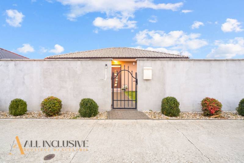 Rodinný dům v Gabčíkovu s plotem, bránou a ozdobnými keři.