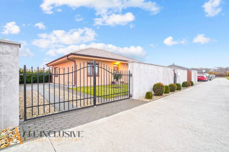 Rodinný dům v Gabčíkovu s kovanou bránou, upravenou zahradou a parkovací plochou.