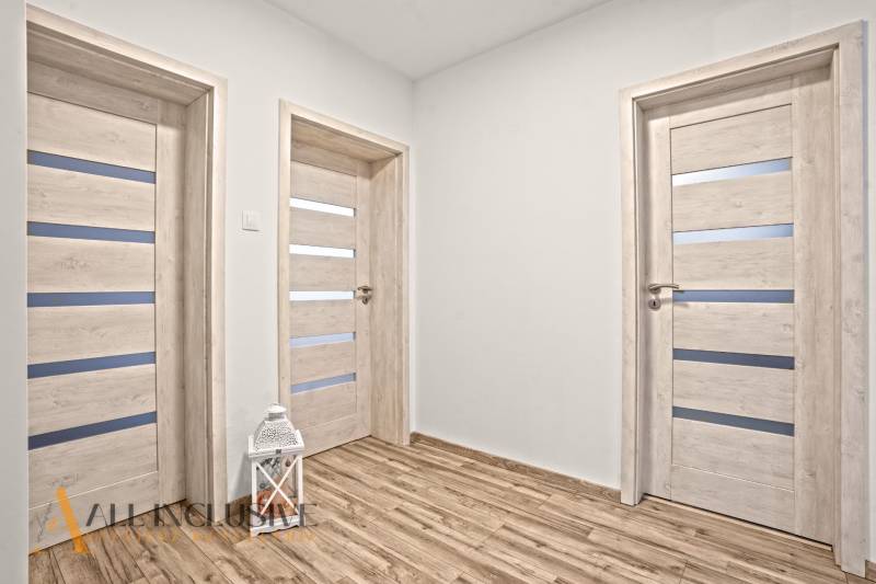 Interiér rodinného domu s podlahou s dřevěným dekorem a bílými dveřmi.