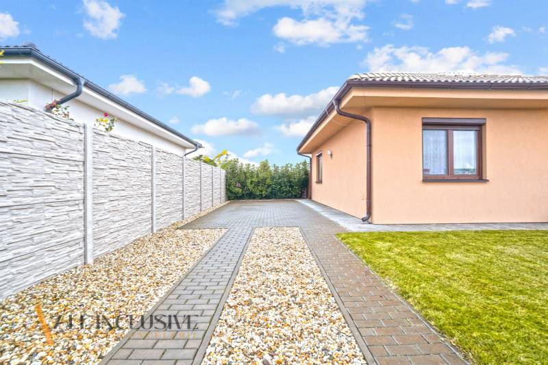 Rodinný dům v Gabčíkovu se zpevněnou příjezdovou cestou, kamenným plotem a udržovaným trávníkem.