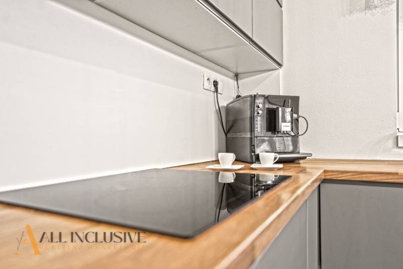 Kuchyně v rodinném domě s kávovarem a varnou deskou na dřevěném dekoru.