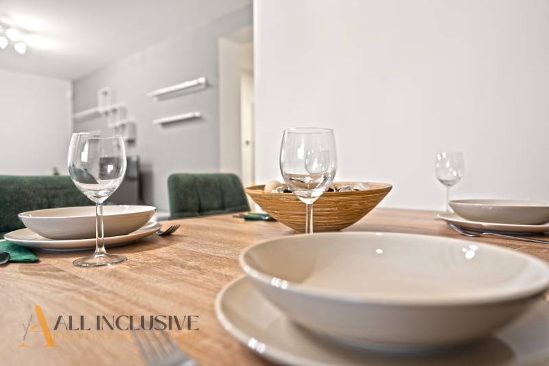 Jídelní stůl se sklenicemi, talíři a miskou v interiéru rodinného domu.