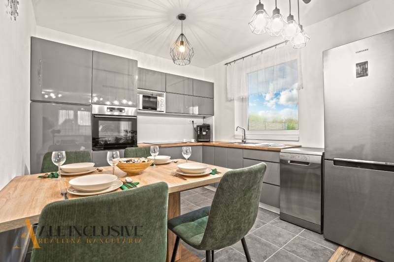 Moderní kuchyně v rodinném domě s dřevěným dekorem stolu a několika spotřebiči.