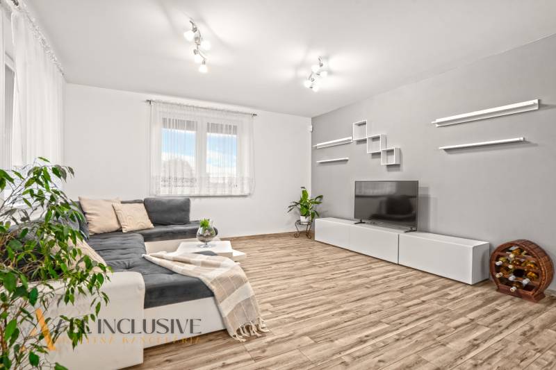 Obývací pokoj v rodinném domě s pohovkou, televizorem a podlahou s dřevěným dekorem.