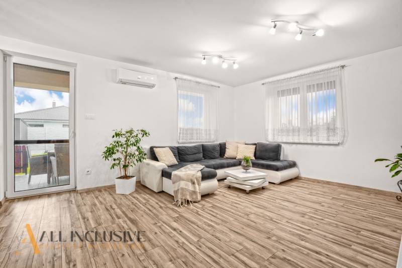 Obývací pokoj v rodinném domě s rohovou sedačkou a podlahou s dřevěným dekorem.