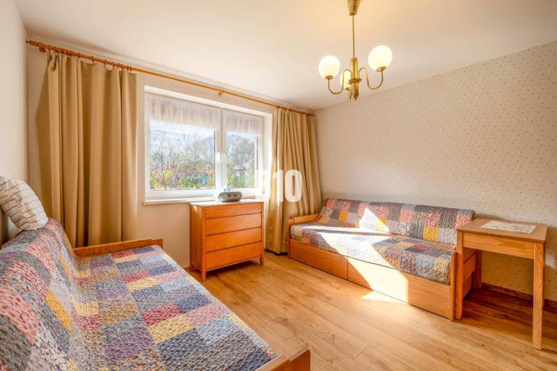 Pokoj v rodinném domě s postelemi, dřevěným dekorem a pestrými přikrývkami.