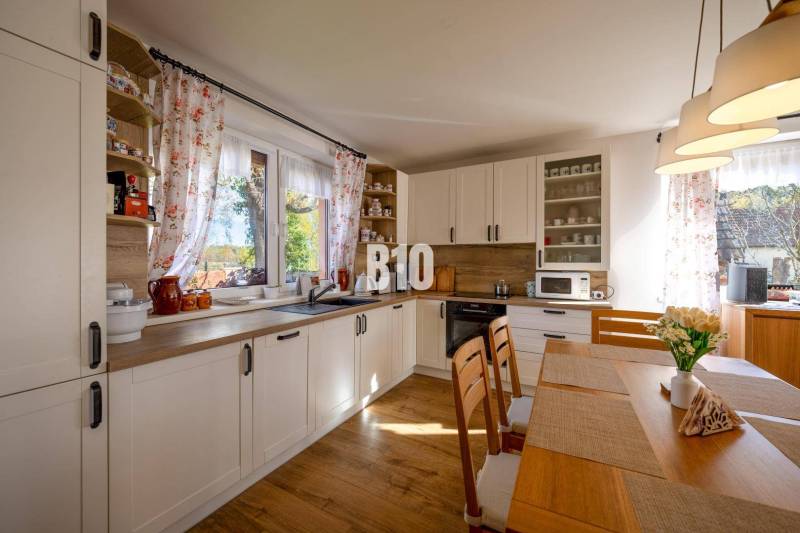 Kuchyně v rodinném domě s podlahou s dřevěným dekorem a světlým nábytkem.