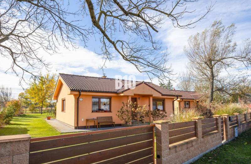 Rodinný dům v Bíkových Humencích s předzahrádkou a stromy na upraveném pozemku.