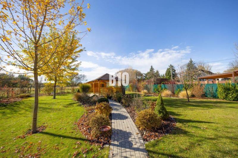 Zahrada v Bílkovej Humenci s altánkem a stromy ozdobenými barevnými listy v rodinném domě.