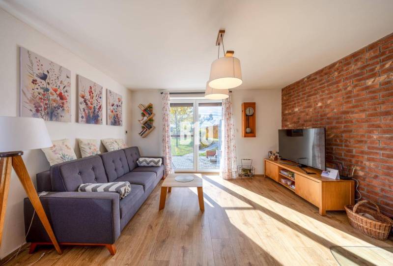 Obývací pokoj v rodinném domě s pohovkou, cihlovou stěnou a podlahou s dřevěným dekorem.