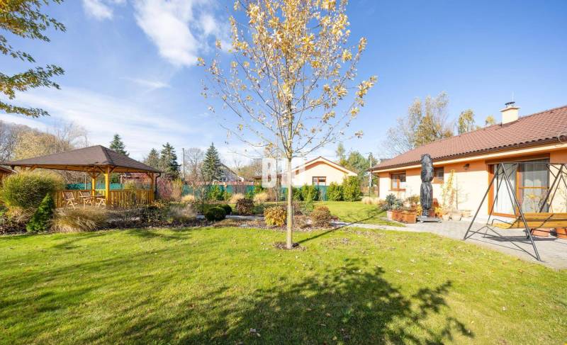 Zahrada s altánkem u rodinného domu v Bílkove Humenci, obklopená zelení.