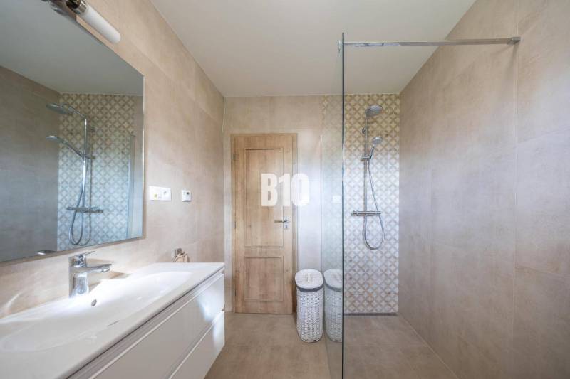 Koupelna s keramickými obklady, sprchovým koutem a zrcadlem v rodinném domě.