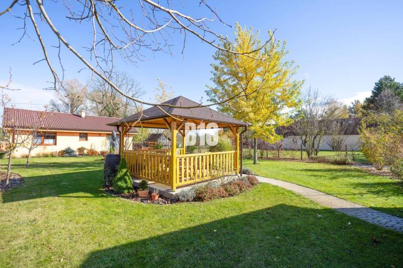 Zahrada rodinného domu v Bílkových Humencích s altánkem a upraveným trávníkem.