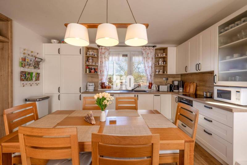 Kuchyně v rodinném domě s dřevěným dekorem a jídelním stolem.