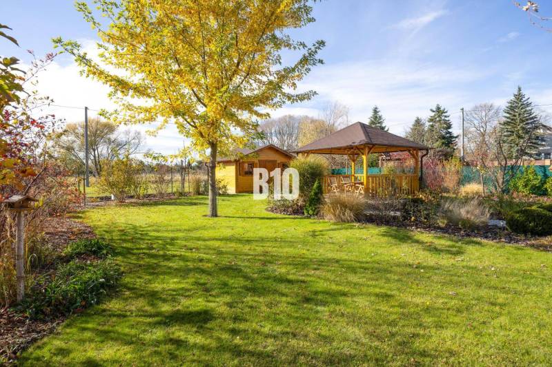 Zahrada rodinného domu v Bílkovej Humence s altánkem a zeleným trávníkem.