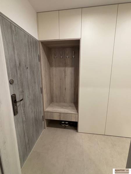 Vstupní chodba se skříňkami a věšáky v 2-pokojovém bytě, dekor dřeva na dveřích.