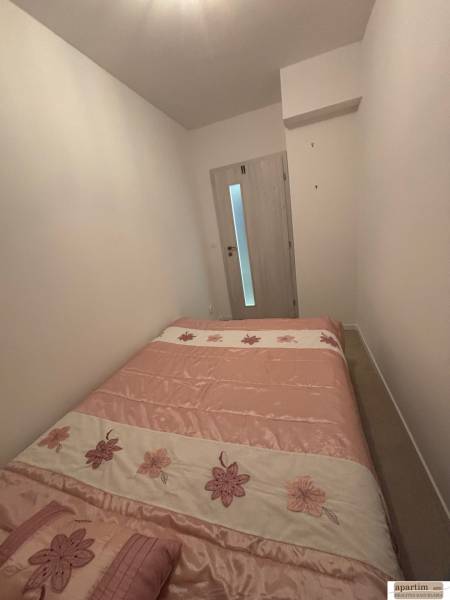 Ložnice v dvoupokojovém bytě s postelí s květinovým motivem a světlými stěnami.