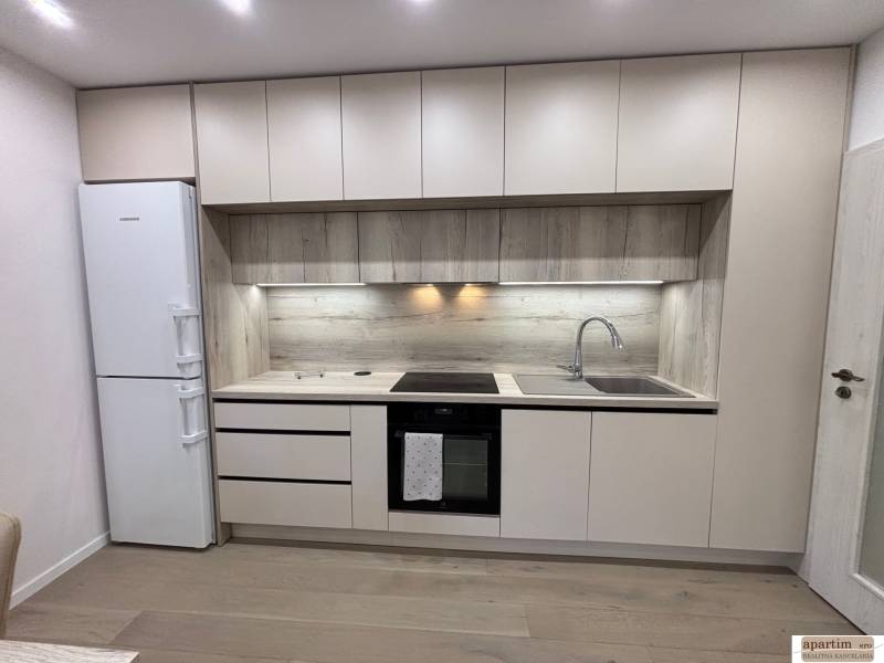 Kuchyňská linka s dřevěným dekorem a vestavěnými spotřebiči v 2pokojovém bytě.