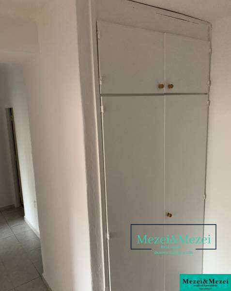 Bílý vestavěný úložný prostor a dlažba v 2-pokojovém bytě.