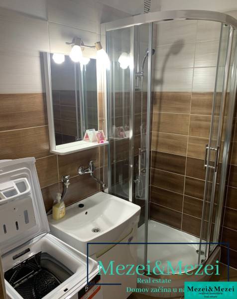 Koupelna s umyvadlem, pračkou a sprchovým koutem v 2pokojovém bytě.