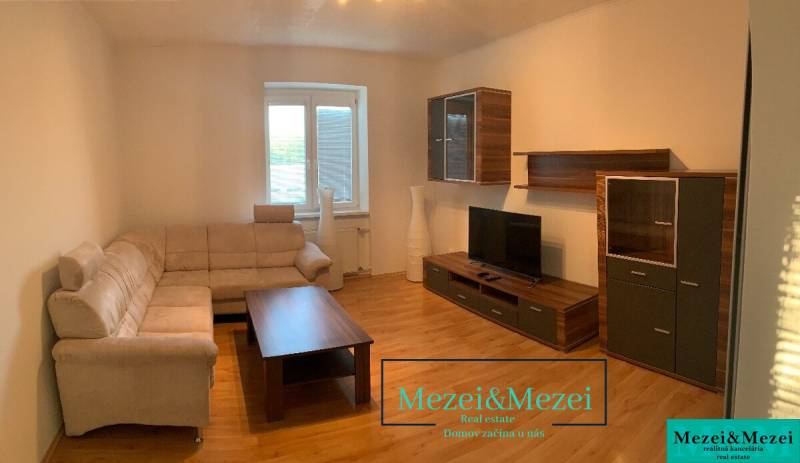 Obývací pokoj s béžovou sedačkou, dřevěným nábytkem a podlahou s dřevěným dekorem.