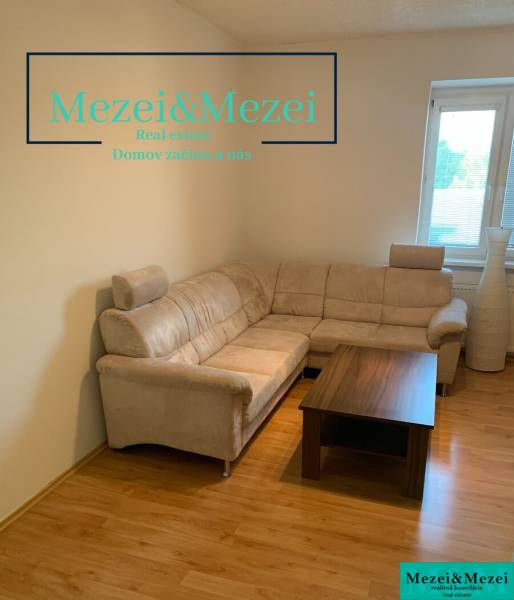 Obývací pokoj v 2pokojovém bytě s rohovou sedačkou a stolkem na podlaze s dřevěným dekorem.