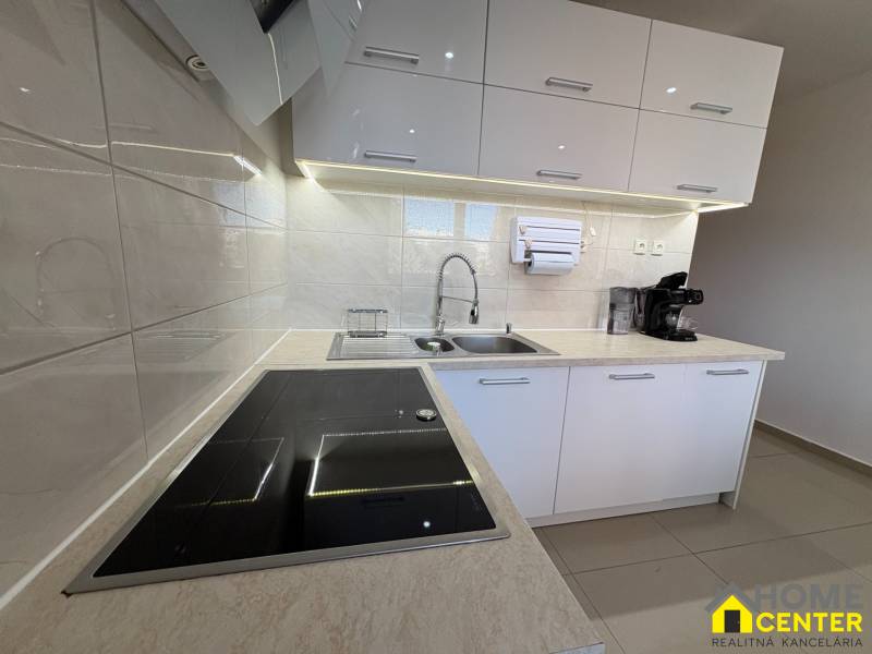 Elegantní kuchyně v 3-pokojovém bytě s bílými skříňkami a indukční varnou deskou.